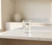 Glass of water on a white marble kitchen island, with a softly blurred neutral background and natural light